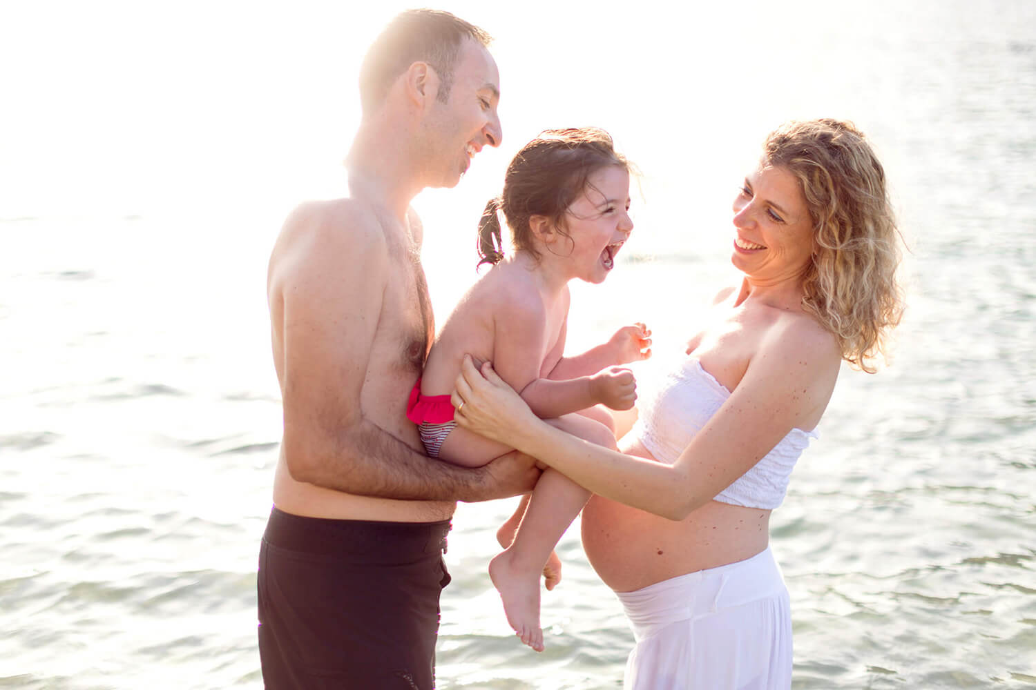 Famiglia che gioca al mare durante un servizio fotografico di gravidanza alla Spezia