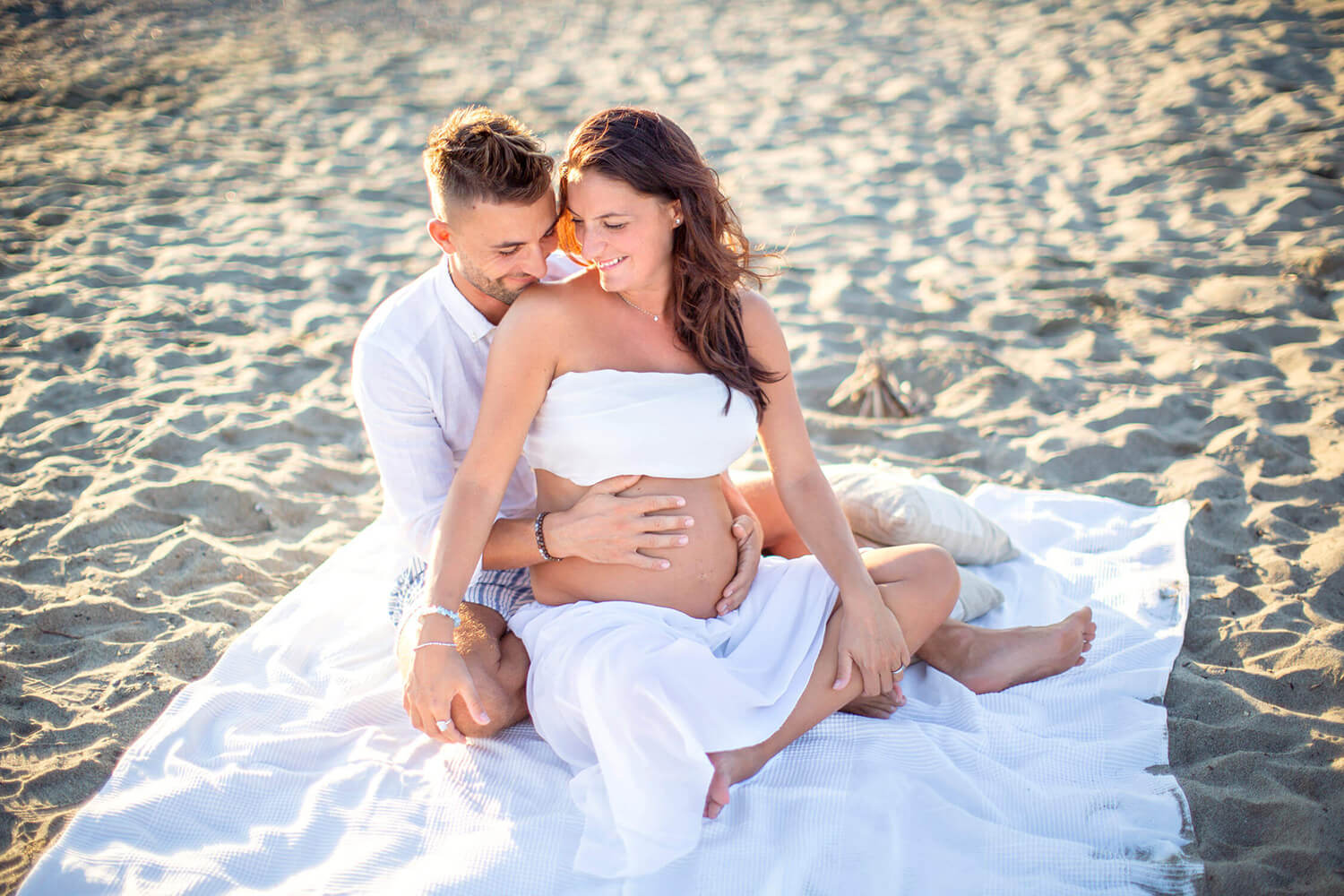 Coppia in spiaggia a La Spezia durante un servizio fotografico di gravidanza