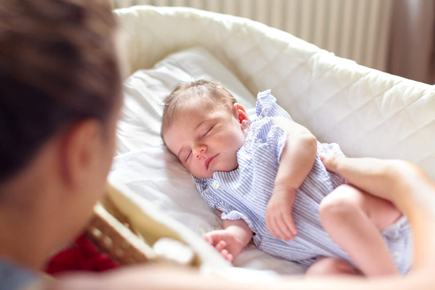 Mamma che guarda il suo bambino in culla fotografata durante un servizio fotografico newborn in casa a La Spezia