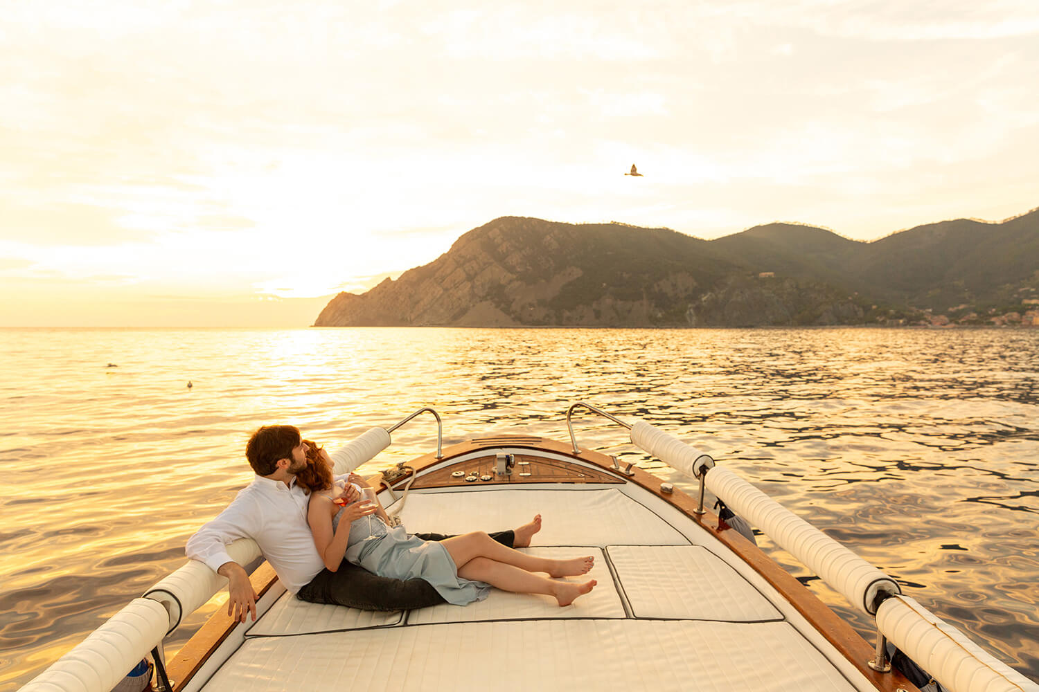 Couple on a boat looking at the scenery at sunset in Cinque Terre, after a marriage proposal