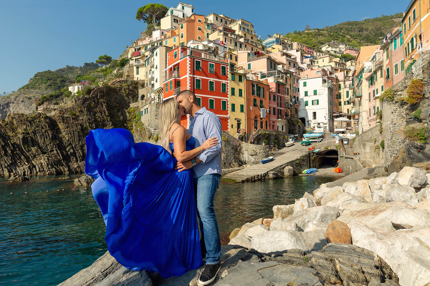Girl with a long blue dress kissing her fiancè in Riomaggiore, Cinque Terre