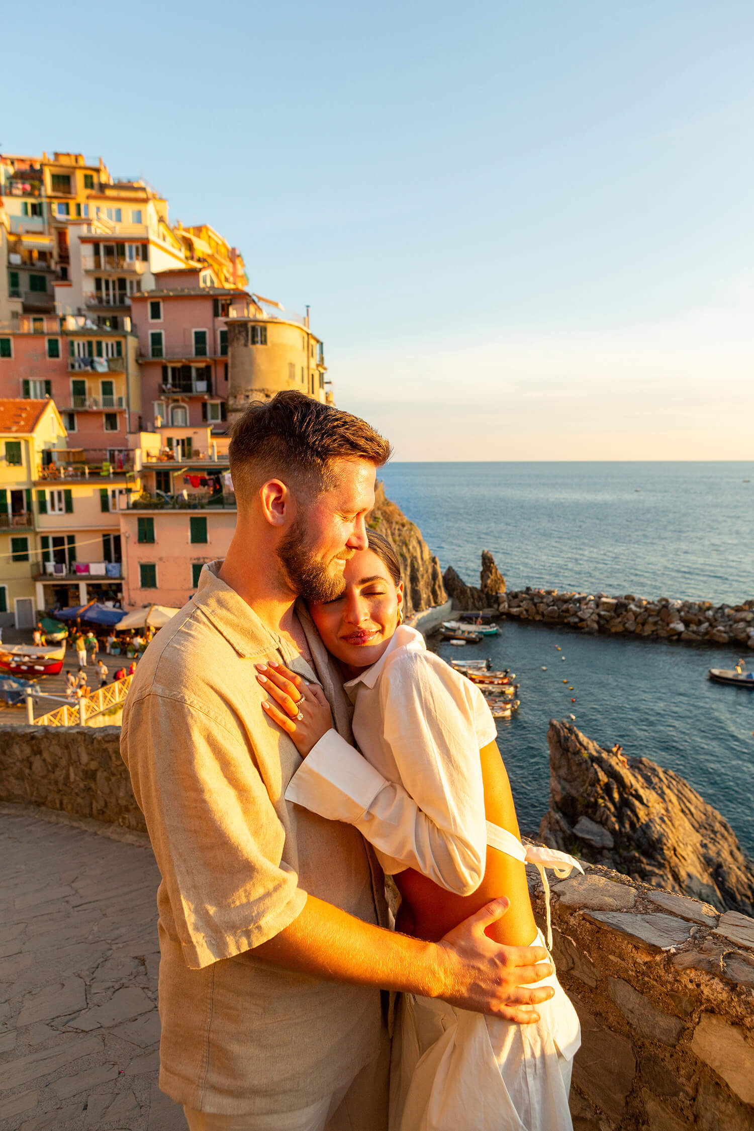 Romantic couple at sunset hugging in Manarola, Cinque Terre, after a surprise proposal