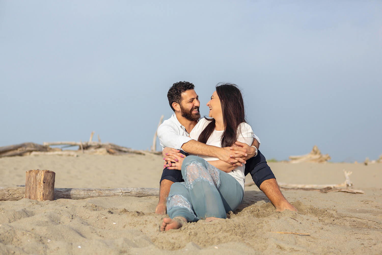 Coppia che sorride in spiaggia durante un servizio prematrimoniale
