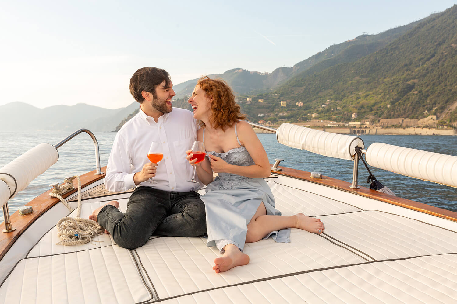 Couple celebrating their engagement on a boat in Cinque Terre drinking an Aperol Spritz