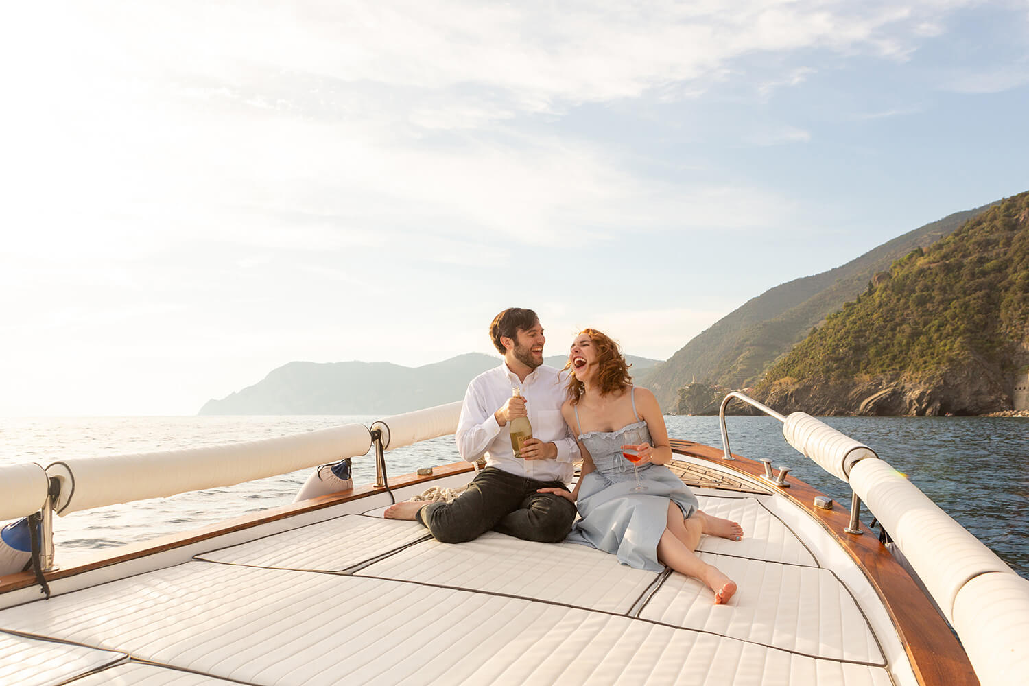 Couple on a boat popping champagne to celebrate their engagement in Cinque Terre