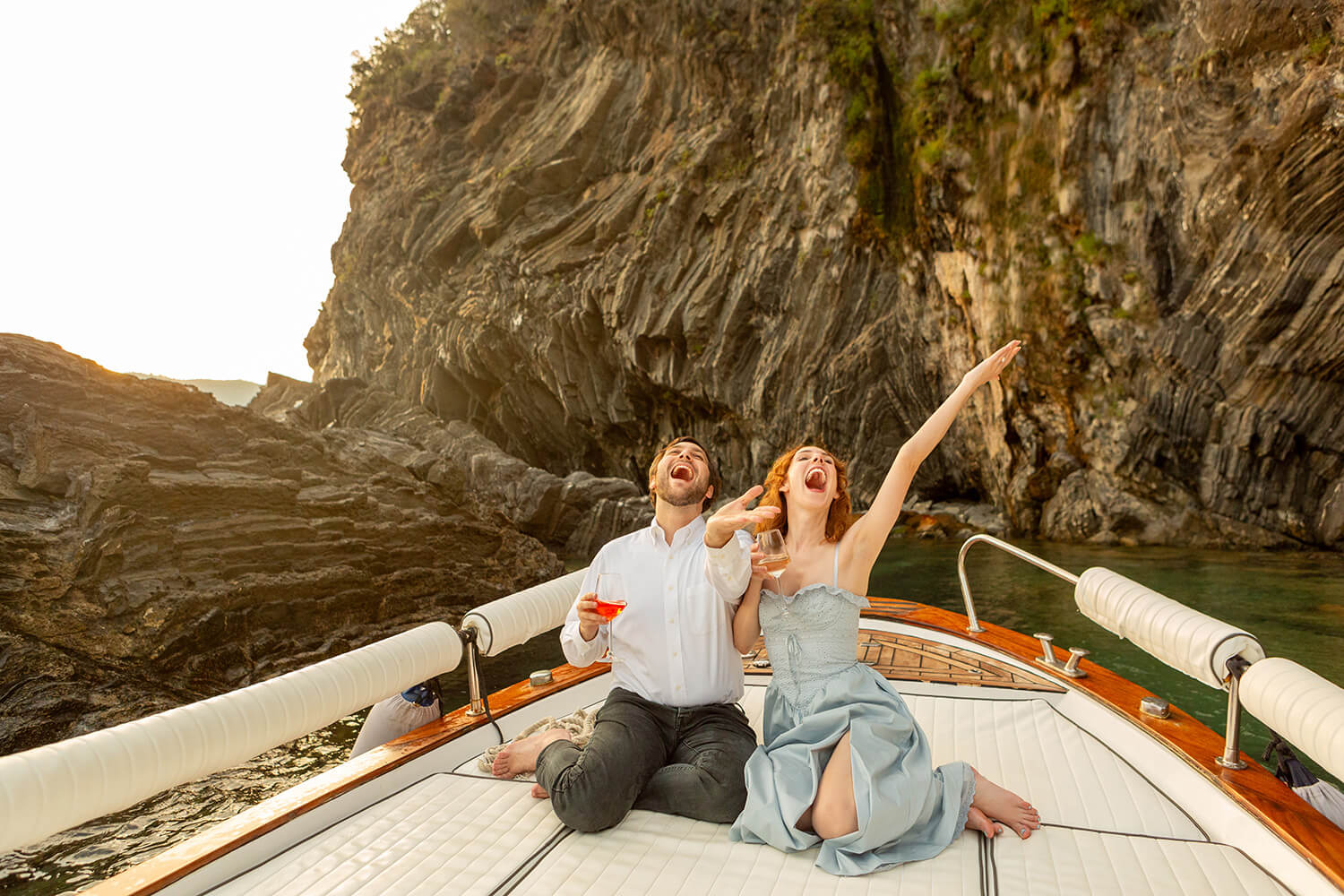 Couple singing and drinking an Aperol Spritz on a boat in Cinque Terre to celebrate their engagement