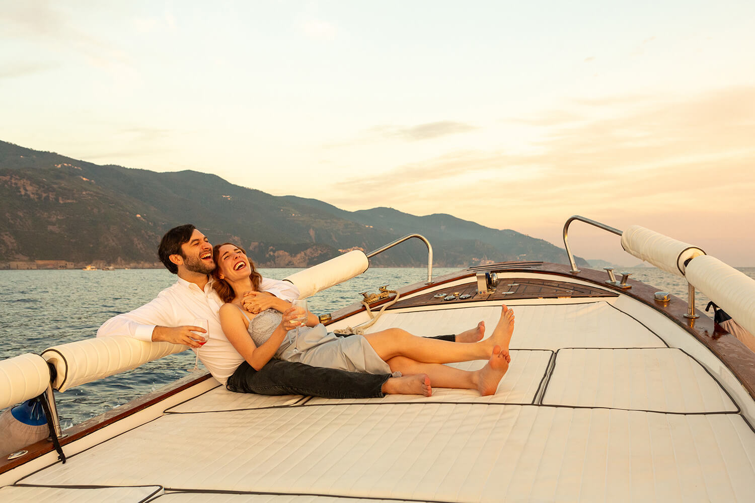 Couple laughing and hugging on a boat at sunset in Cinque Terre after a marriage proposal